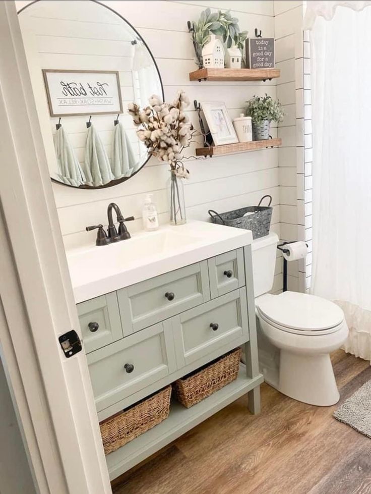 a white toilet sitting next to a sink in a bathroom under a large round mirror