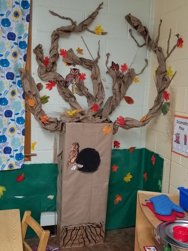 a classroom area with a tree made out of paper and other things on the wall