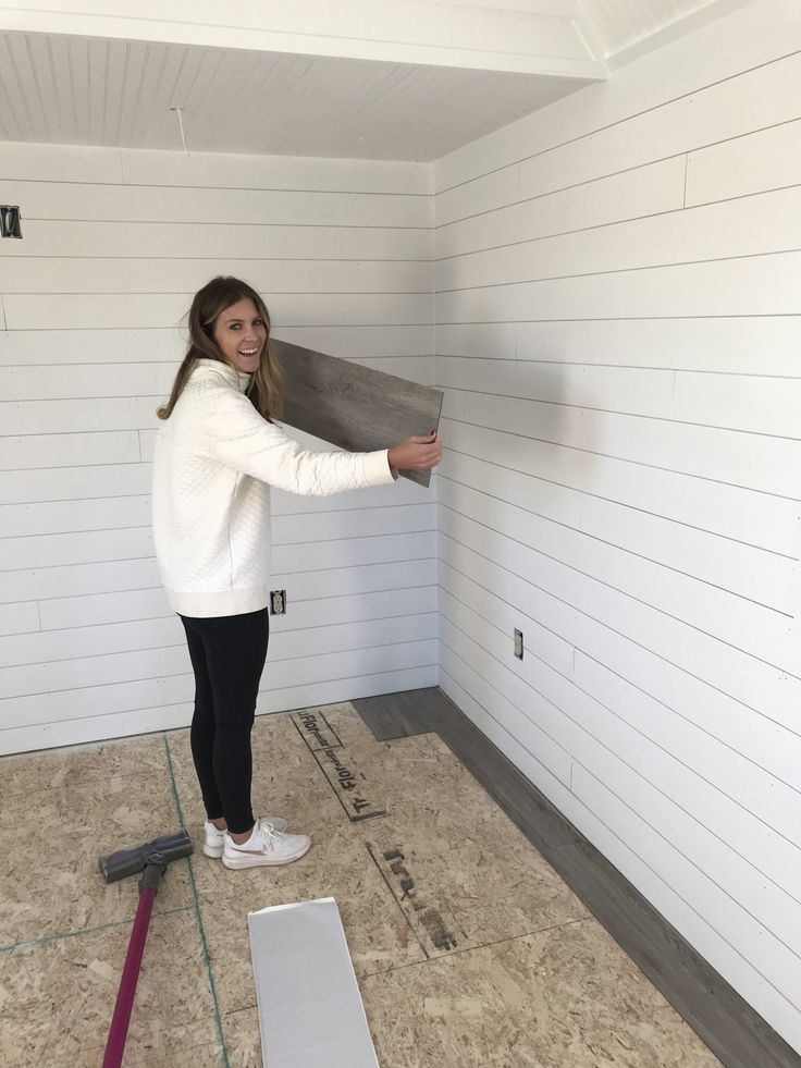 a woman standing in a room holding up a piece of wood