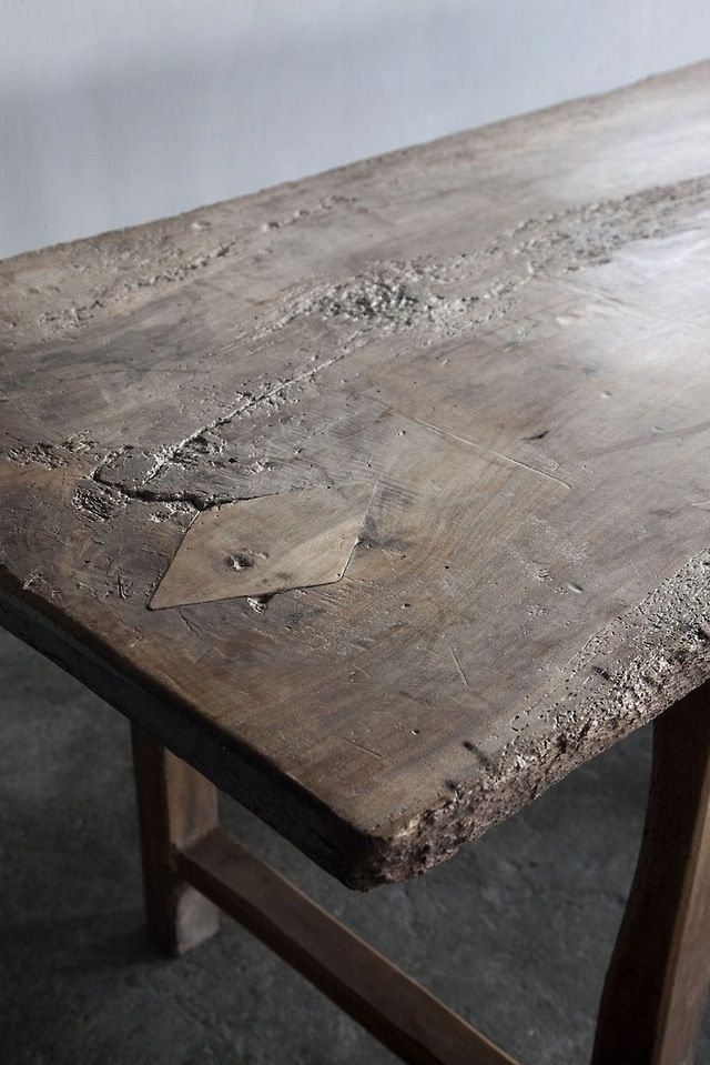 an old wooden table with metal legs in a warehouse or office space, showing the wood grain that is peeling and chipped