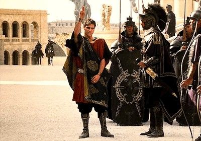 three men dressed in roman costumes standing next to each other with their hands raised up