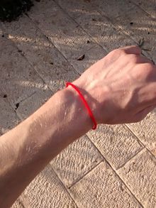 a person wearing a red bracelet on their wrist