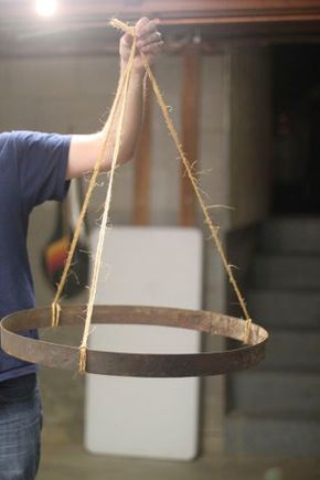 a man is holding a large round object with rope on it's sides and hanging from the ceiling