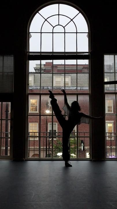 a person standing in front of a window with their arms up and one leg on the ground