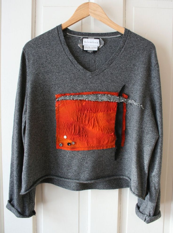 an orange and grey sweater hanging on a white door