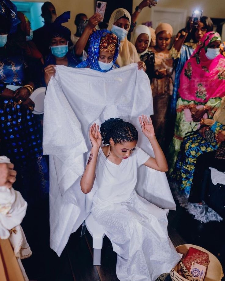 a woman sitting in front of a group of people holding up a white piece of cloth