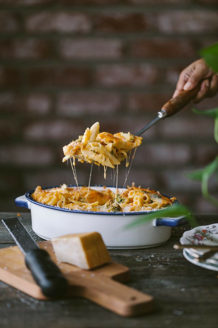 a person scooping some food out of a casserole dish with cheese and spinach