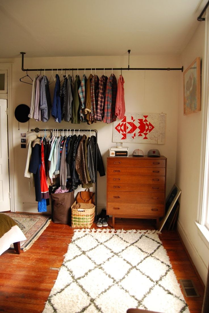 a bedroom with clothes hanging on the wall and a rug in front of an open door