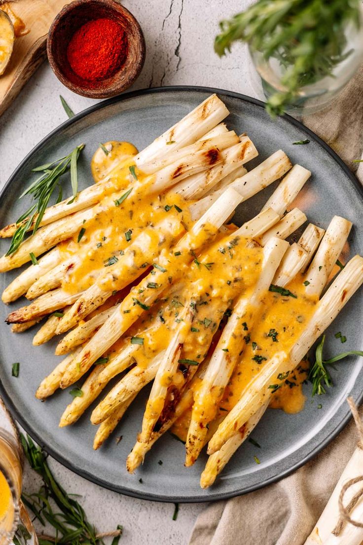 grilled asparagus on a plate with cheese sauce and herbs next to it