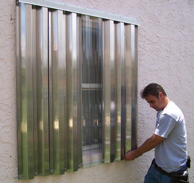 a man in white shirt standing next to window with metal bars on the side of it