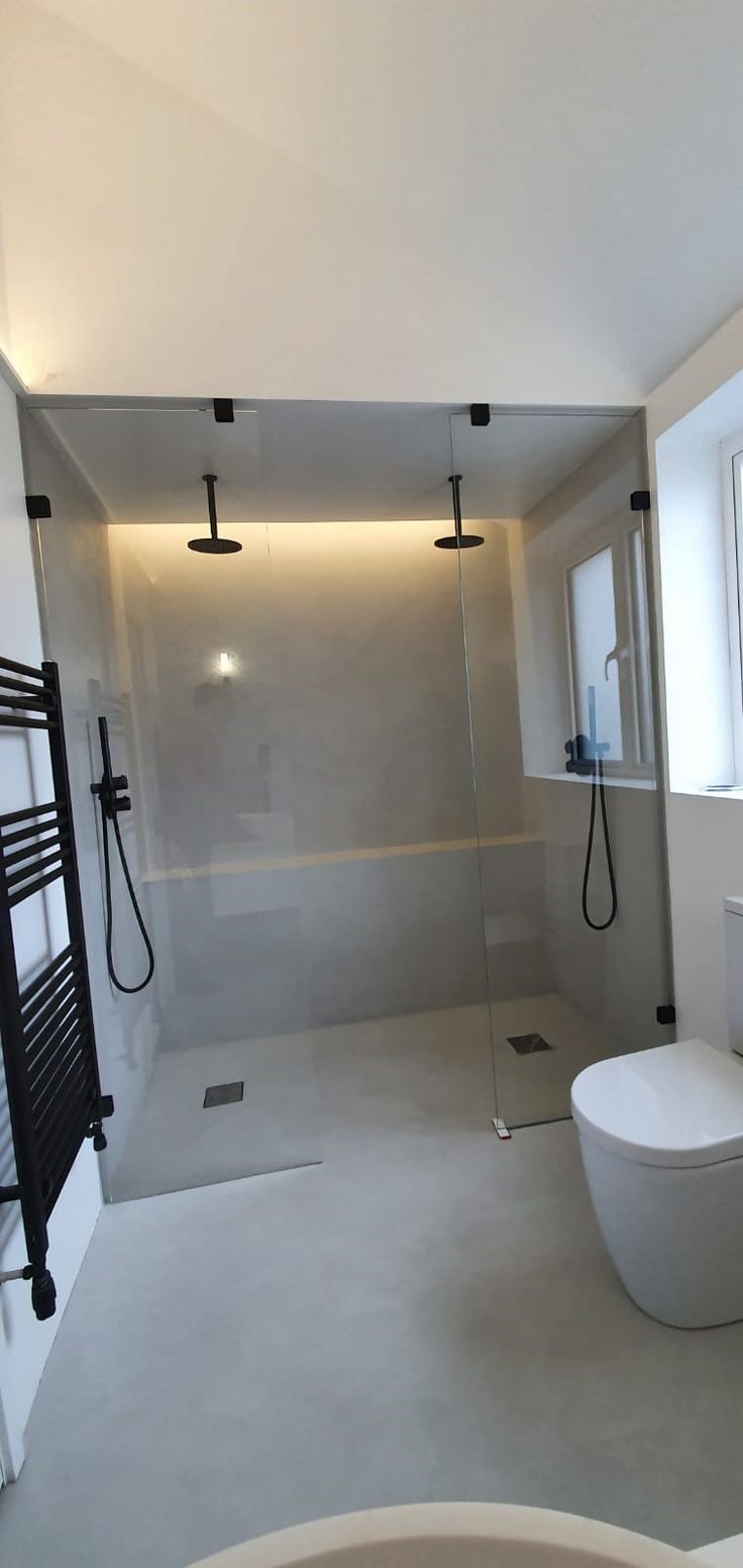 a bathroom with a toilet, sink and shower in it's center wall next to a window