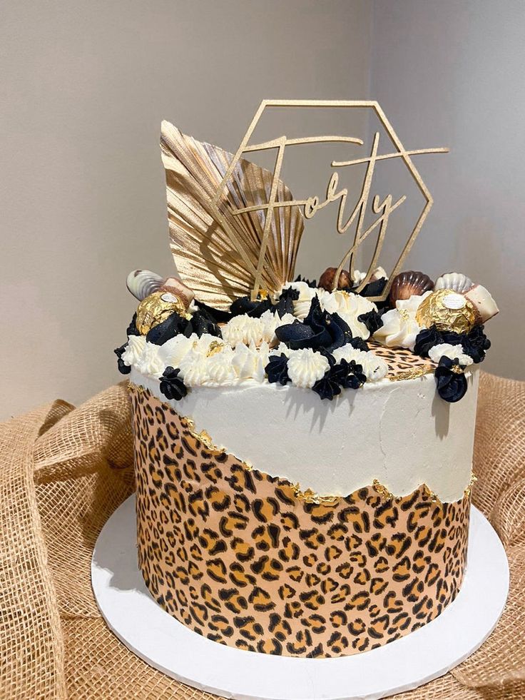 a leopard print cake with white frosting and gold decorations