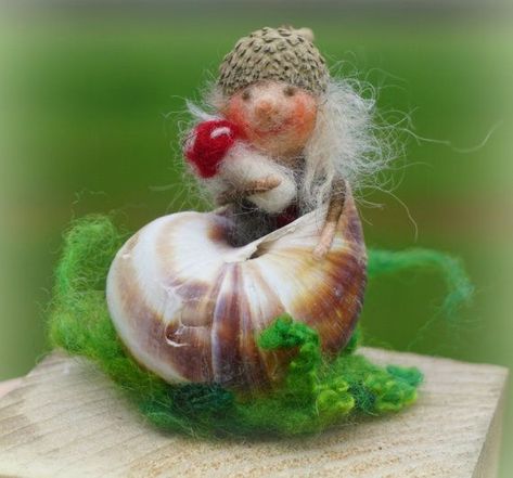 a small doll sitting on top of a piece of wood