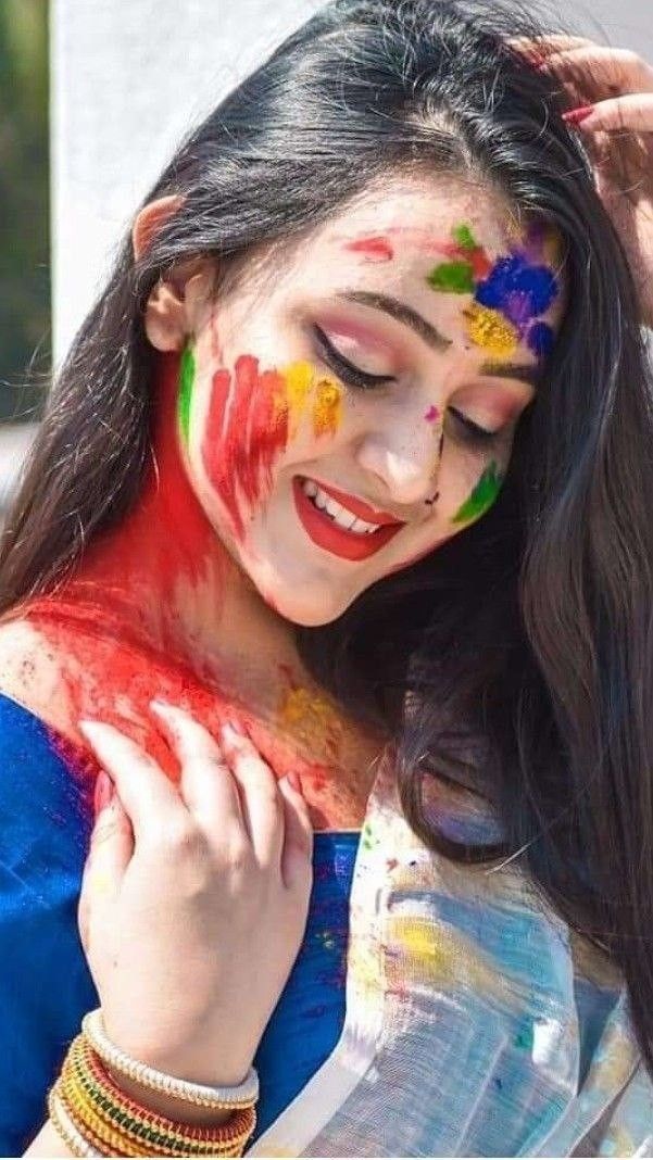 a woman with her face painted in bright colors and holding her hands to her head