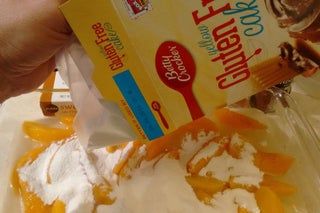 a person is pouring orange juice into a bowl with whipped cream on top and an orange wedge in the middle