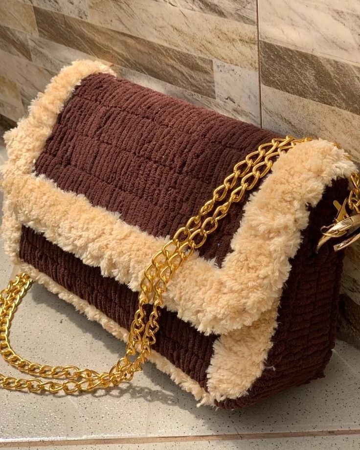 a brown and white purse with gold chains hanging from it's side on a counter