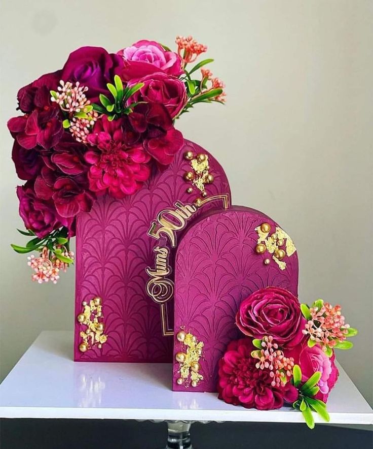 two purple bags with pink flowers on top of them and a bouquet of red roses in the middle