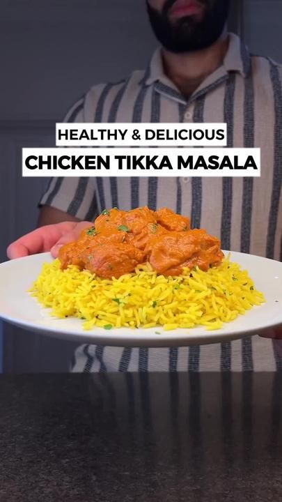 a man is holding a plate with rice and chicken tikka masala on it