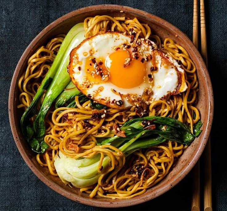 a bowl filled with noodles and an egg on top of it next to chopsticks