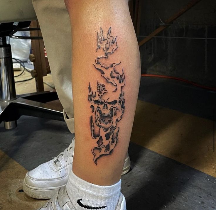 a man's leg with a tattoo on it that has a skull in the middle