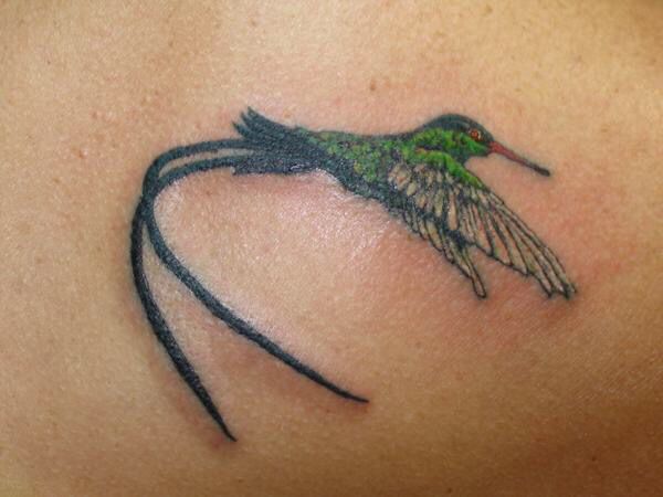 a hummingbird tattoo on the back of a woman's shoulder and chest area