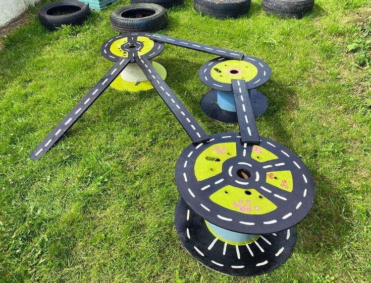 an upside down toy in the grass with tires on it's sides and wheels attached to each other