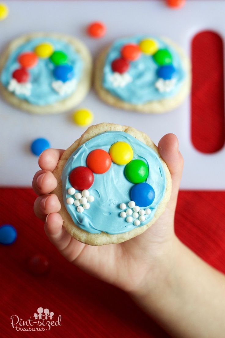 a hand holding a cookie with candy on it