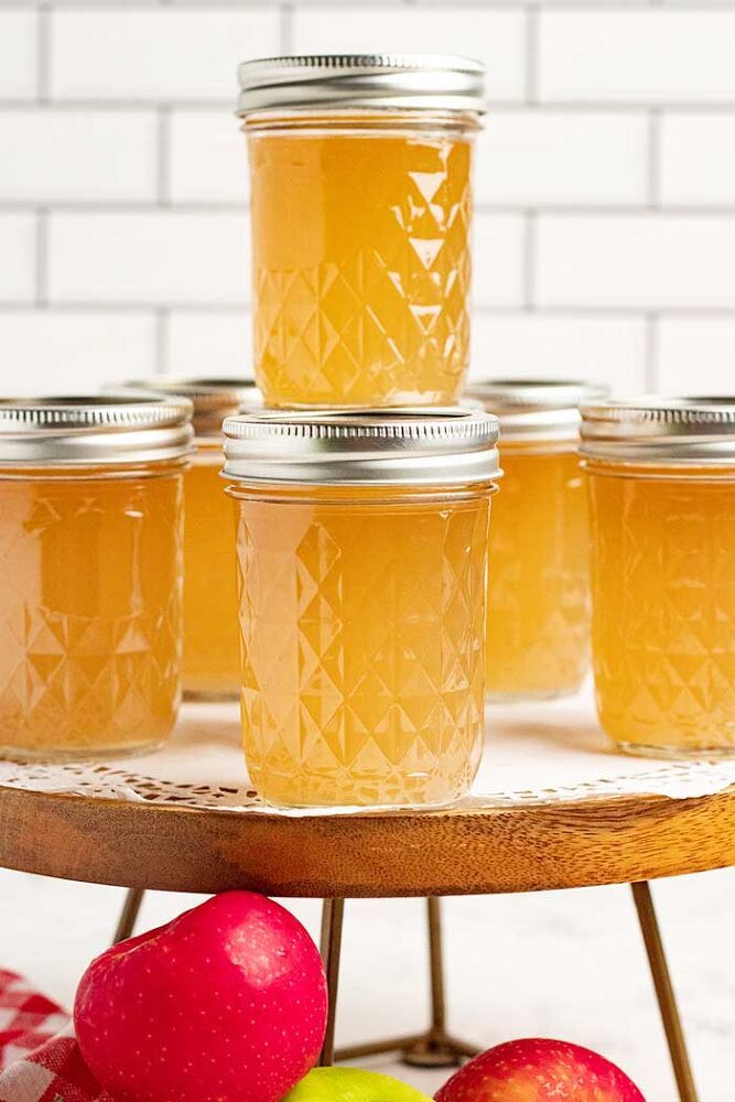 four jars of apple cider sitting on top of a table next to apples and pears