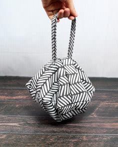 a hand holding a black and white origami bag