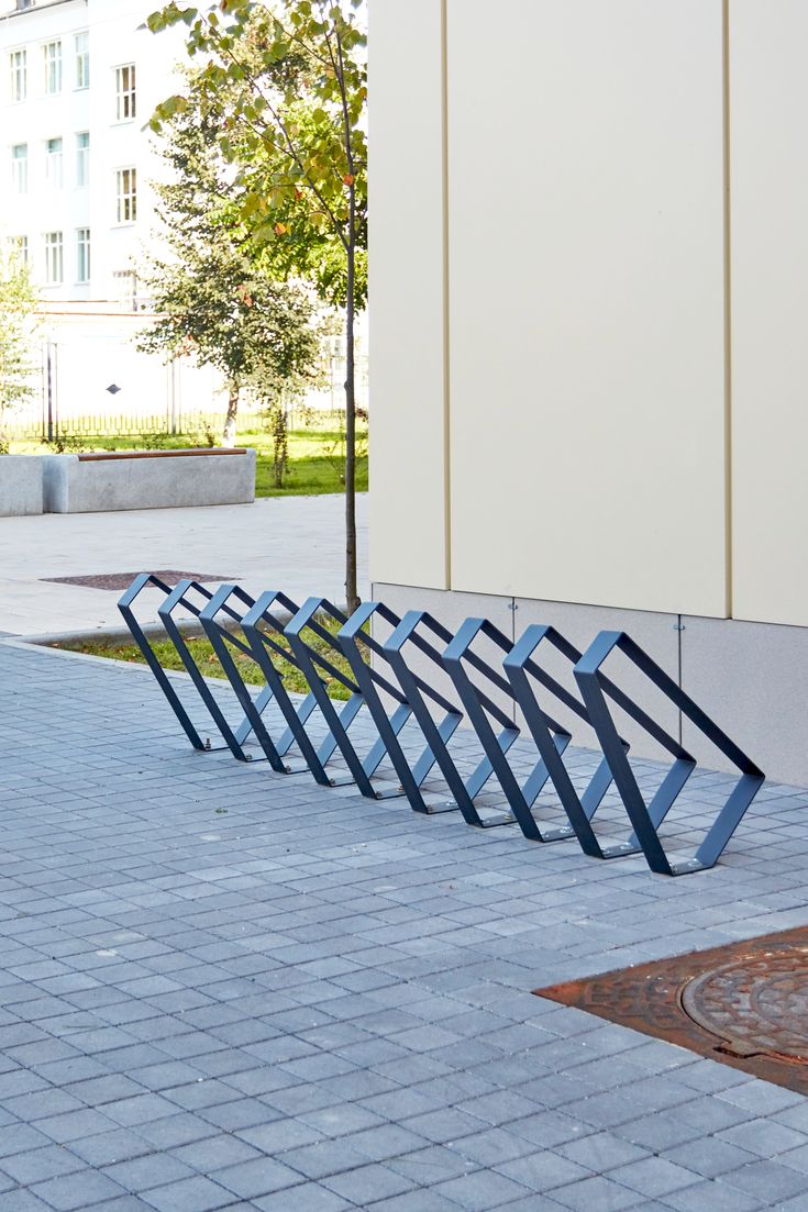 four blue metal benches sitting on the side of a brick road next to a building