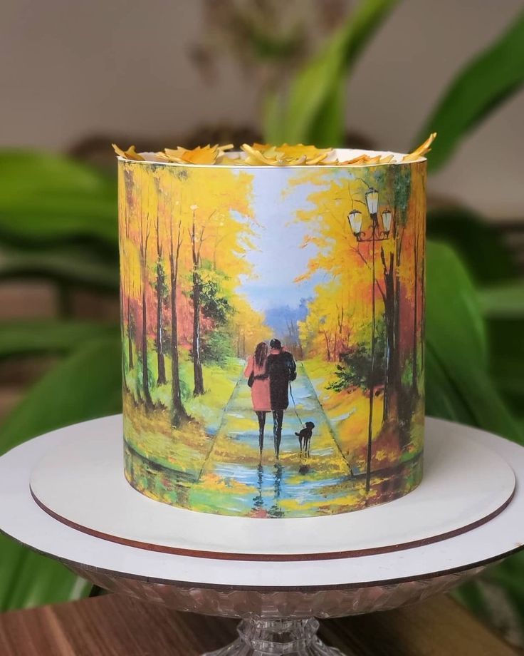 a cake with a painting of two people walking down the street holding an umbrella and dog