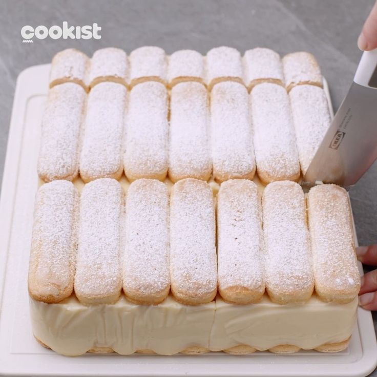 a person cutting into some food on top of a white tray with a knife in it