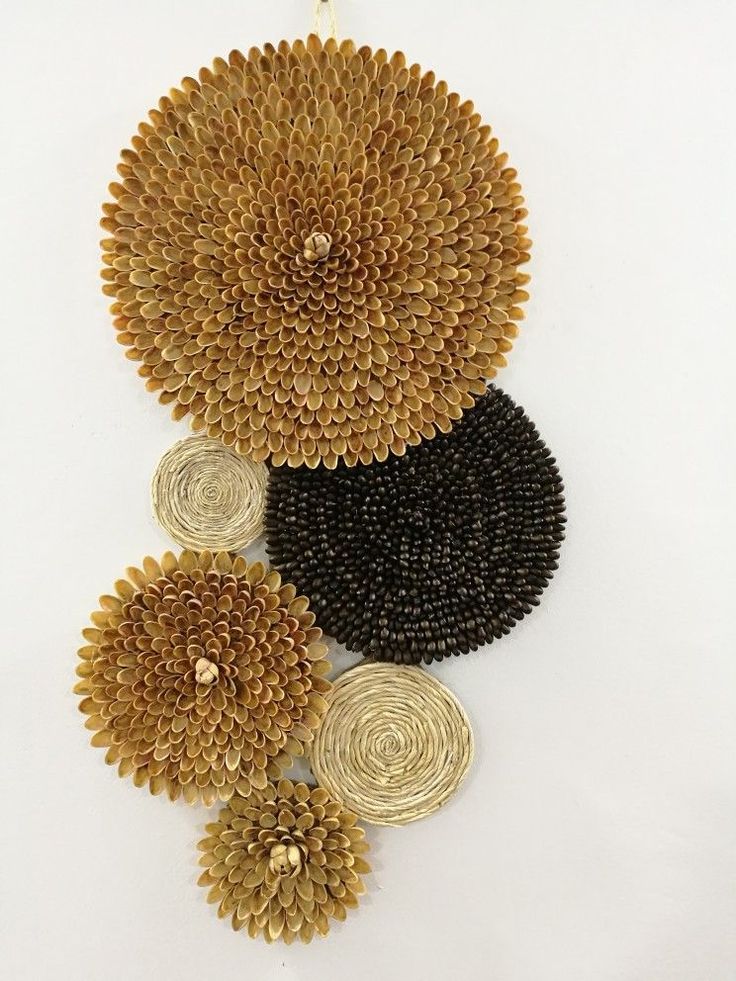 three pieces of gold and black beaded art hanging on a white wall next to each other