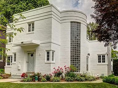 a white house with many windows and flowers in the front yard