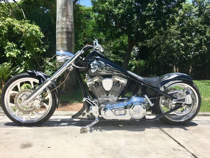 a black and silver motorcycle parked on the side of the road next to some trees