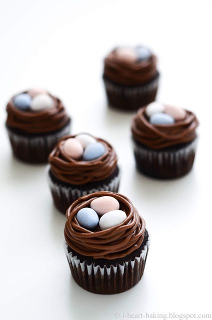 chocolate cupcakes decorated with eggs and chocolate icing on a white table top