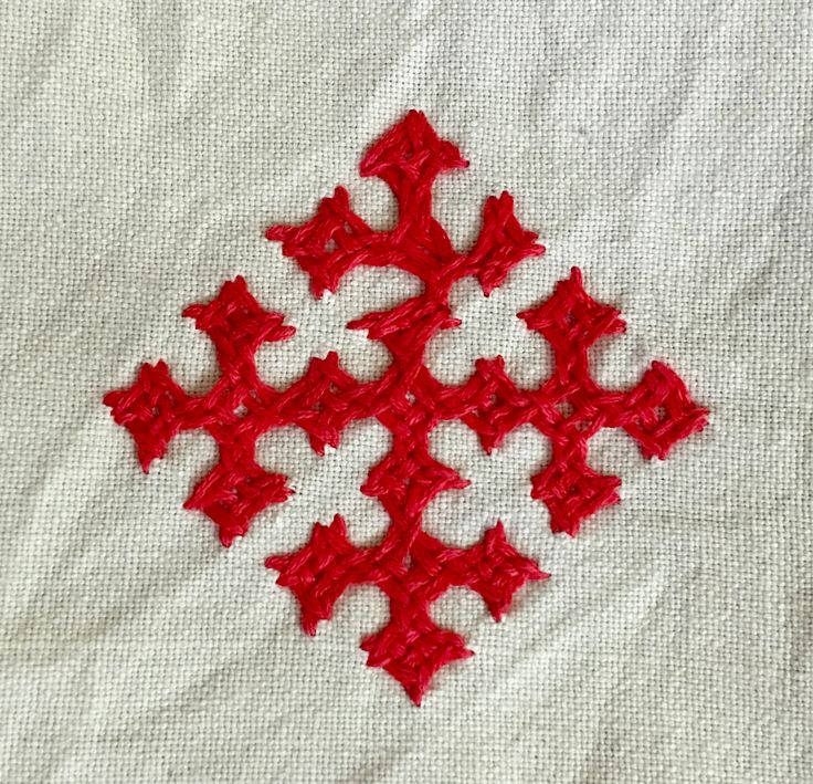 a red piece of cloth with small stars on it and some thread in the middle