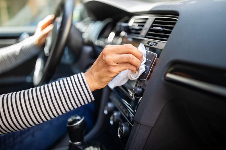 a woman is cleaning the dashboard of her car