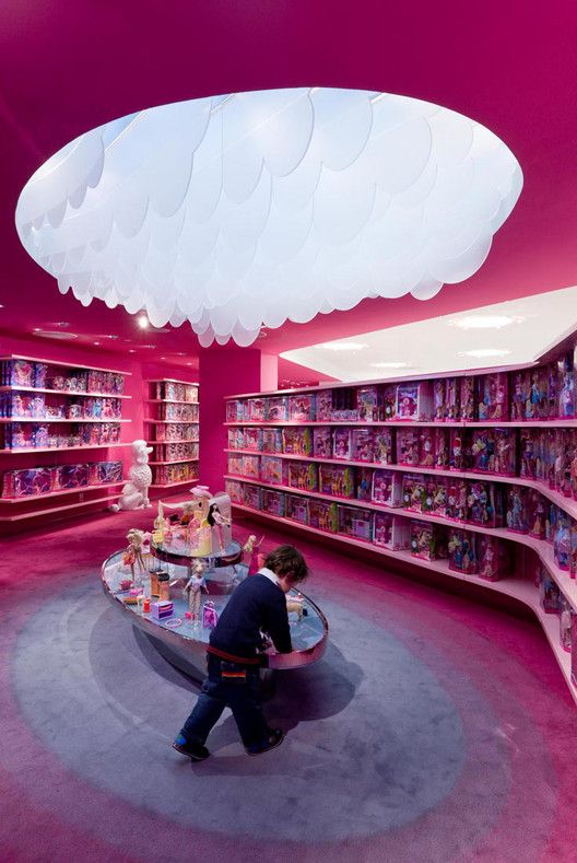 there is a man that is looking at items on the table in the store's pink shelves