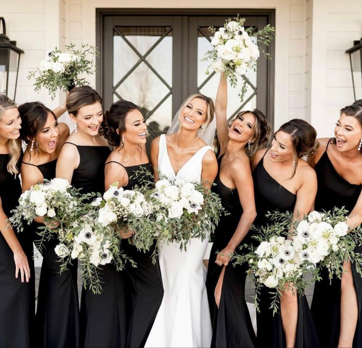 a group of women standing next to each other in front of a door holding bouquets