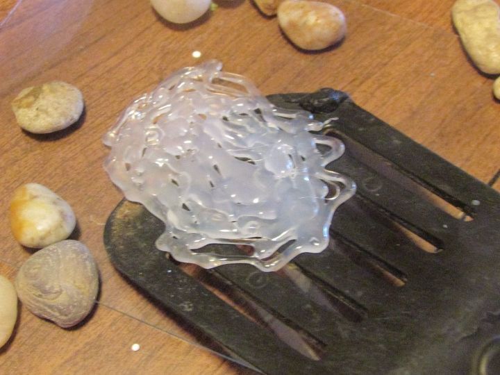 a plastic object sitting on top of a wooden table next to rocks and other items