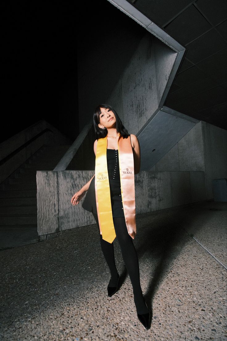 a woman wearing a yellow and black scarf standing in front of an escalator