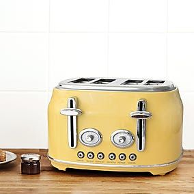 a yellow toaster sitting on top of a wooden counter next to a plate with food