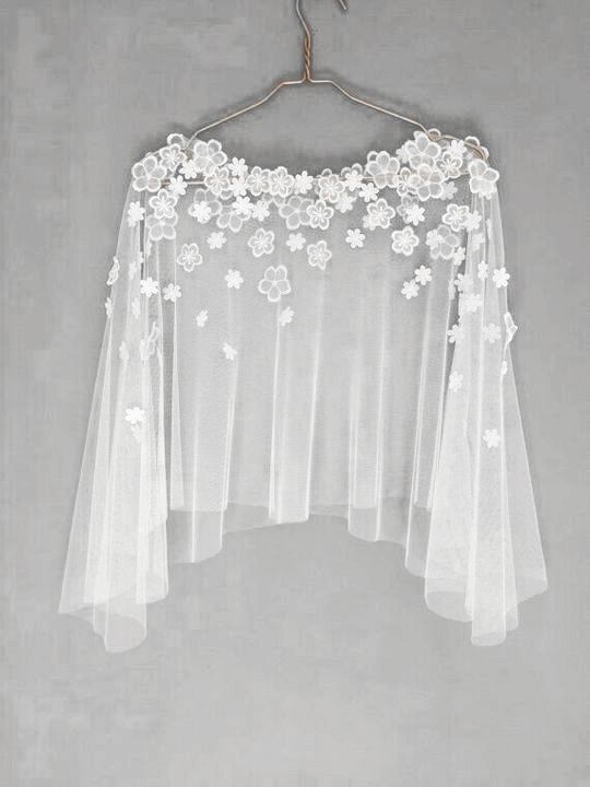 a white wedding veil hanging on a hanger with flowers and leaves attached to it