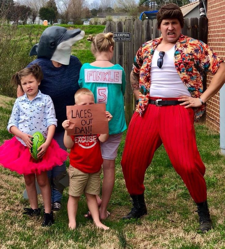 two adults and three children holding signs in front of a brick building