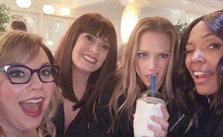 four women are posing for the camera with drinks in their hands and one is holding a straw