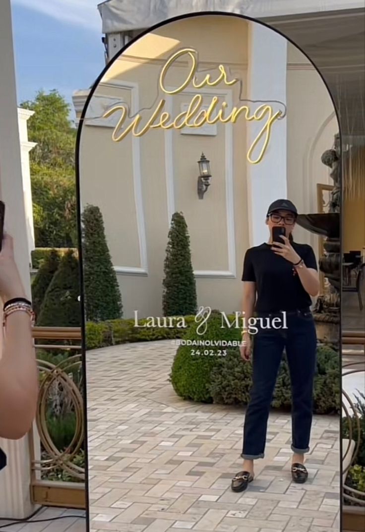 a woman taking a selfie in front of a building with the words our wedding written on it