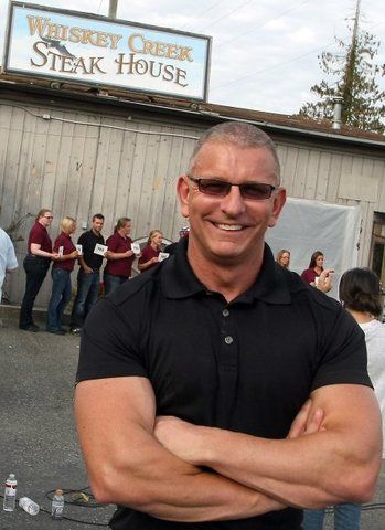 a man standing in front of a building with his arms crossed and smiling at the camera