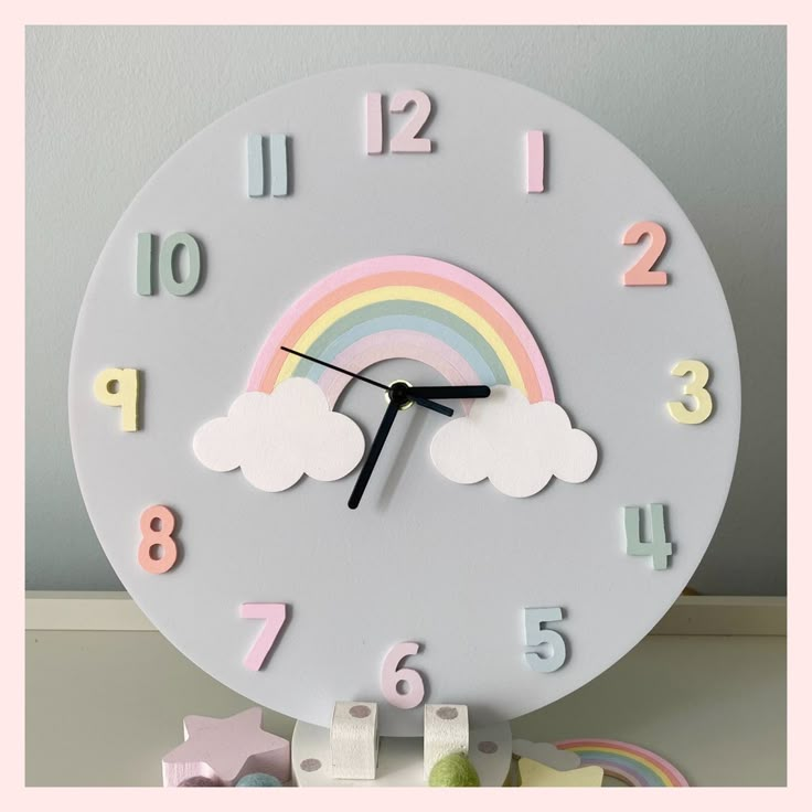 a clock with clouds, rainbows and stars on the sides is sitting on a table