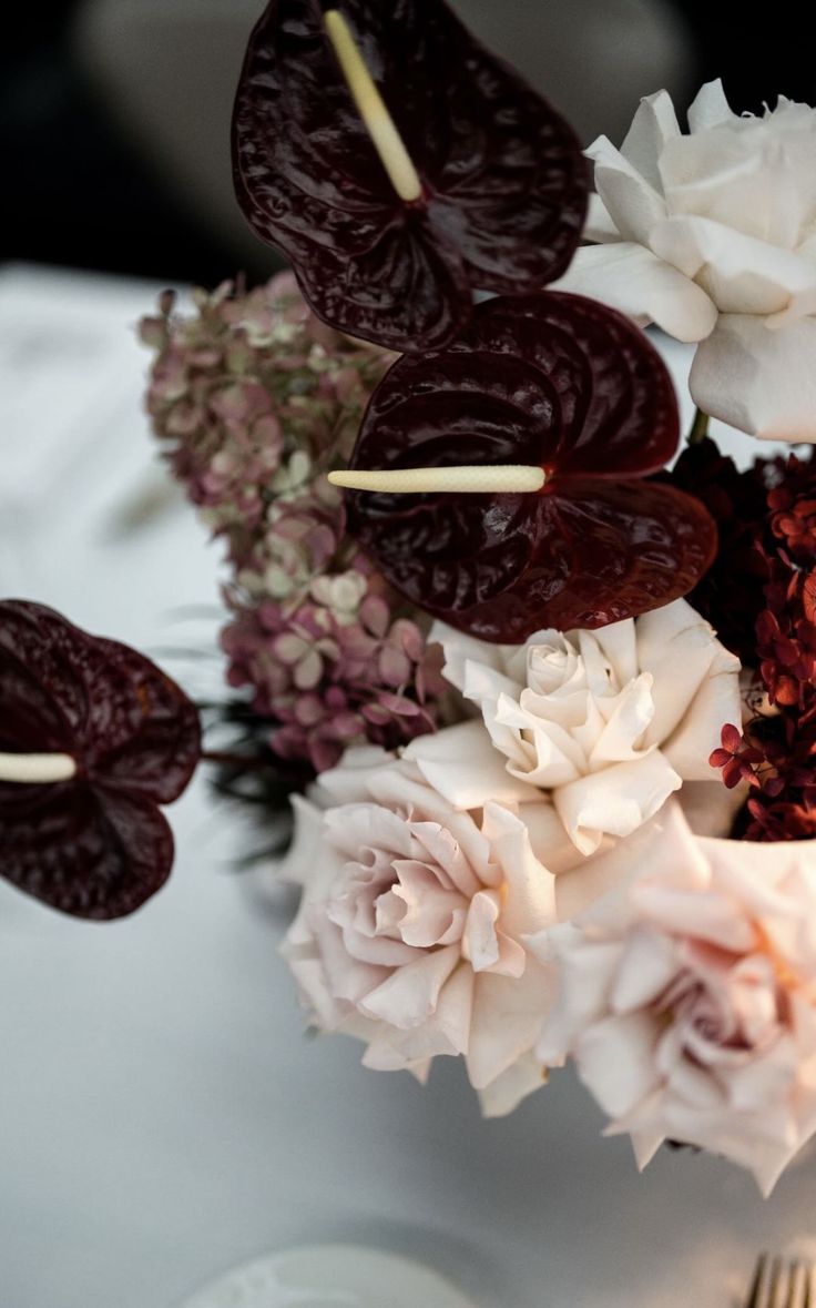 flowers are arranged in a vase on a white tablecloth with silverware and utensils